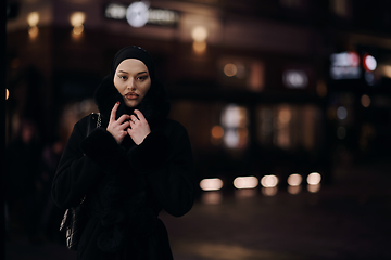 Image showing Muslim woman walking on urban city street on a cold winter night wearing hijab