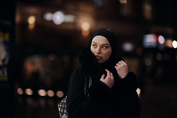 Image showing Muslim woman walking on urban city street on a cold winter night wearing hijab