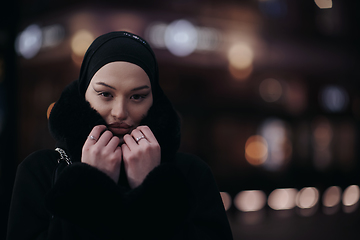 Image showing Muslim woman walking on urban city street on a cold winter night wearing hijab