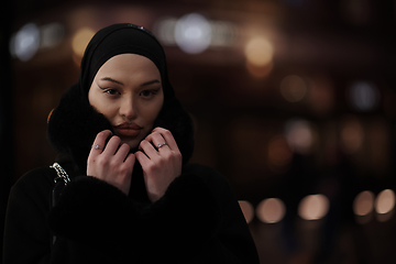 Image showing Muslim woman walking on urban city street on a cold winter night wearing hijab