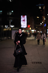 Image showing Muslim woman walking on urban city street on a cold winter night wearing hijab