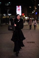 Image showing Muslim woman walking on urban city street on a cold winter night wearing hijab