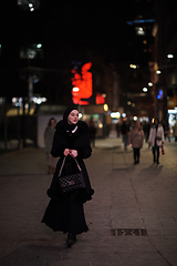 Image showing Muslim woman walking on urban city street on a cold winter night wearing hijab