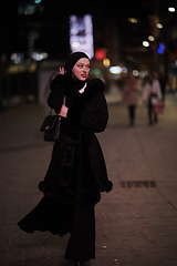 Image showing Muslim woman walking on urban city street on a cold winter night wearing hijab