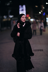 Image showing Muslim woman walking on urban city street on a cold winter night wearing hijab