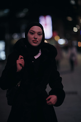 Image showing Muslim woman walking on urban city street on a cold winter night wearing hijab