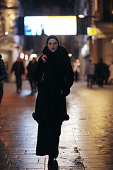 Image showing Muslim woman walking on urban city street on a cold winter night wearing hijab