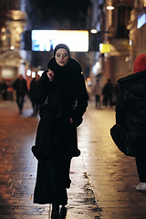 Image showing Muslim woman walking on urban city street on a cold winter night wearing hijab