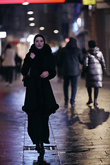 Image showing Muslim woman walking on urban city street on a cold winter night wearing hijab