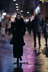 Image showing Muslim woman walking on urban city street on a cold winter night wearing hijab