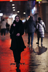 Image showing Muslim woman walking on urban city street on a cold winter night wearing hijab