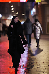 Image showing Muslim woman walking on urban city street on a cold winter night wearing hijab