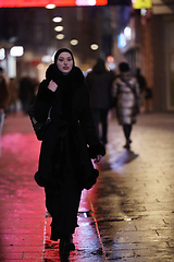 Image showing Muslim woman walking on urban city street on a cold winter night wearing hijab