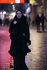 Image showing Muslim woman walking on urban city street on a cold winter night wearing hijab