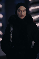 Image showing Muslim woman walking on an urban city street on a cold winter night wearing hijab