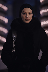 Image showing Muslim woman walking on urban city street on a cold winter night wearing hijab