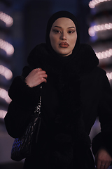 Image showing Muslim woman walking on urban city street on a cold winter night wearing hijab