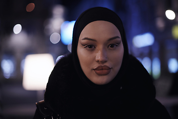 Image showing Muslim woman walking on urban city street on a cold winter night wearing hijab