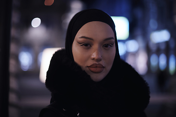 Image showing Muslim woman walking on urban city street on a cold winter night wearing hijab