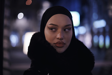 Image showing Muslim woman walking on urban city street on a cold winter night wearing hijab