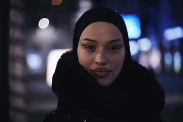 Image showing Muslim woman walking on urban city street on a cold winter night wearing hijab