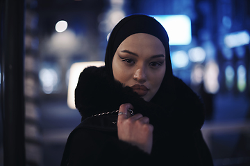 Image showing Muslim woman walking on urban city street on a cold winter night wearing hijab