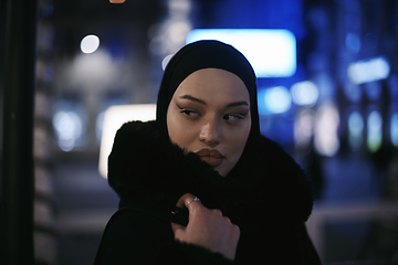 Image showing Muslim woman walking on urban city street on a cold winter night wearing hijab