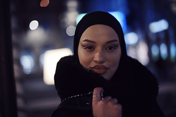 Image showing Muslim woman walking on urban city street on a cold winter night wearing hijab