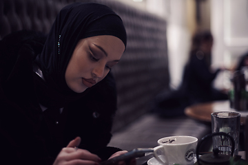 Image showing Muslim woman walking on an urban city street on a cold winter night wearing hijab