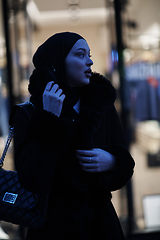 Image showing Muslim woman walking on an urban city street on a cold winter night wearing hijab