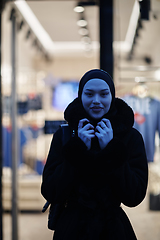 Image showing Muslim woman walking on an urban city street on a cold winter night wearing hijab