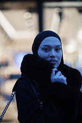 Image showing Muslim woman walking on an urban city street on a cold winter night wearing hijab