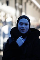 Image showing Muslim woman walking on an urban city street on a cold winter night wearing hijab