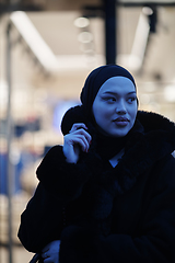 Image showing Muslim woman walking on an urban city street on a cold winter night wearing hijab