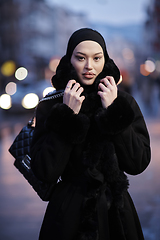 Image showing Muslim woman walking on an urban city street on a cold winter night wearing hijab