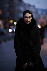 Image showing Muslim woman walking on an urban city street on a cold winter night wearing hijab