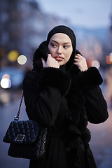 Image showing Muslim woman walking on an urban city street on a cold winter night wearing hijab