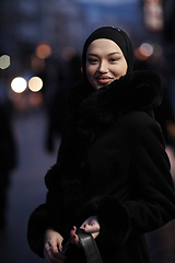 Image showing Muslim woman walking on an urban city street on a cold winter night wearing hijab