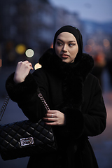 Image showing Muslim woman walking on an urban city street on a cold winter night wearing hijab