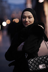 Image showing Muslim woman walking on an urban city street on a cold winter night wearing hijab