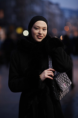 Image showing Muslim woman walking on an urban city street on a cold winter night wearing hijab