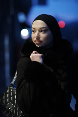 Image showing Muslim woman walking on an urban city street on a cold winter night wearing hijab