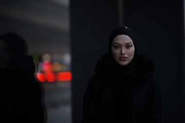 Image showing Muslim woman walking on an urban city street on a cold winter night wearing hijab