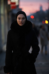 Image showing Muslim woman walking on an urban city street on a cold winter night wearing hijab