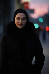 Image showing Muslim woman walking on an urban city street on a cold winter night wearing hijab