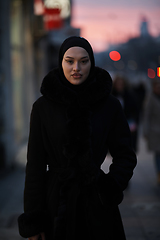 Image showing Muslim woman walking on an urban city street on a cold winter night wearing hijab