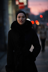 Image showing Muslim woman walking on an urban city street on a cold winter night wearing hijab