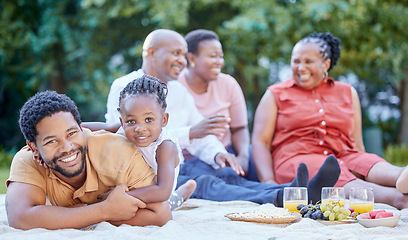 Image showing Portrait of a black father and child at a picnic with family in an outdoor green garden during spring. Smile, happy and african people eating healthy fruit at a outside celebration in a park.