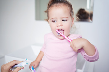 Image showing Baby learning to brush her teeth, dental and oral hygiene. Toothbrush, toothpaste and brushing teeth in child development and routine. Dentist, dentistry and teeth cleaning in young children.