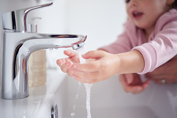 Image showing Hand, water and cleaning with a girl and her mother washing her hands under a tap for hygiene and sanitation during covid in their home. Children, health and grooming in the bathroom of a house